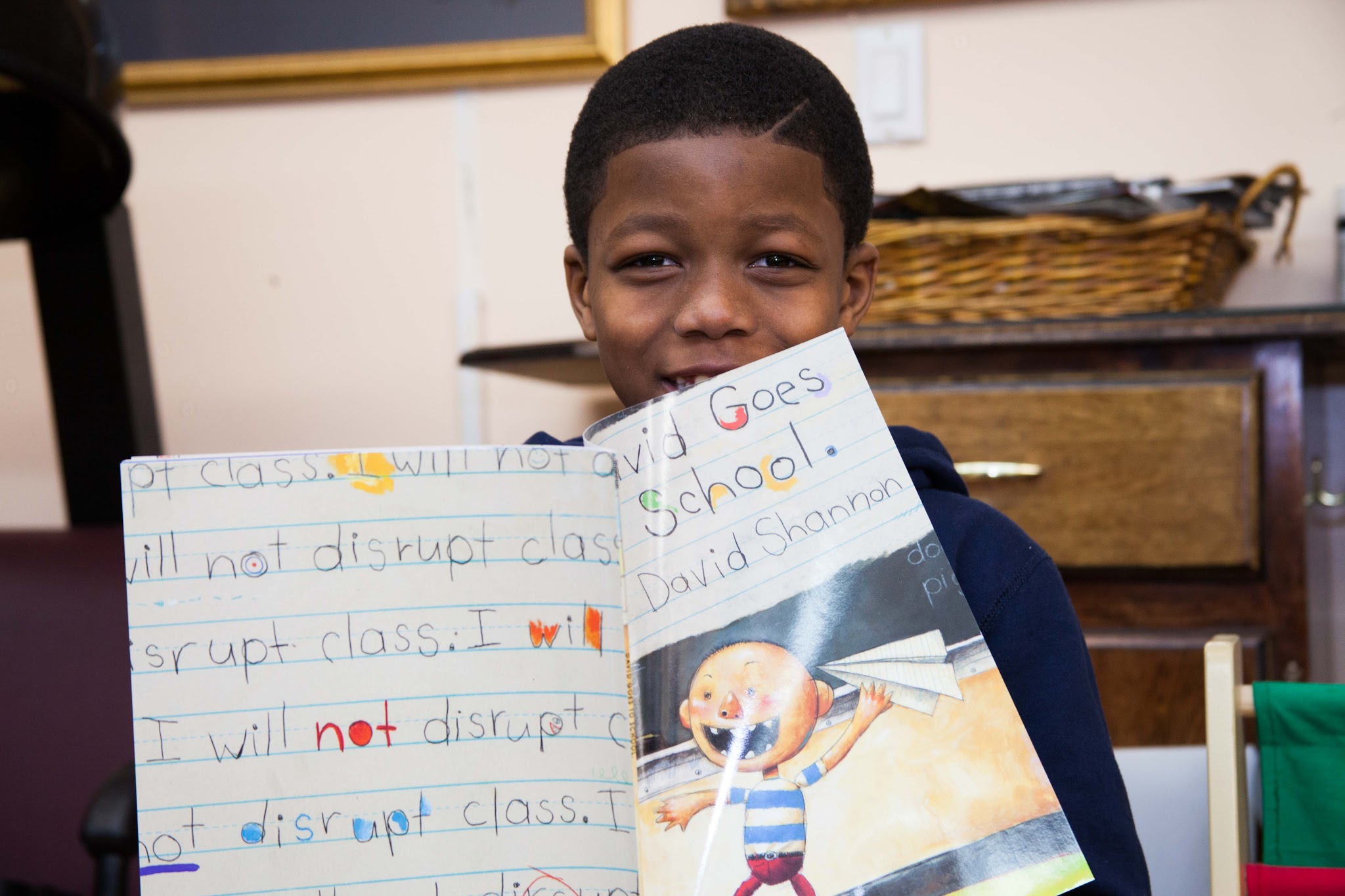 Black boy smiling holding a book up in the barbershop