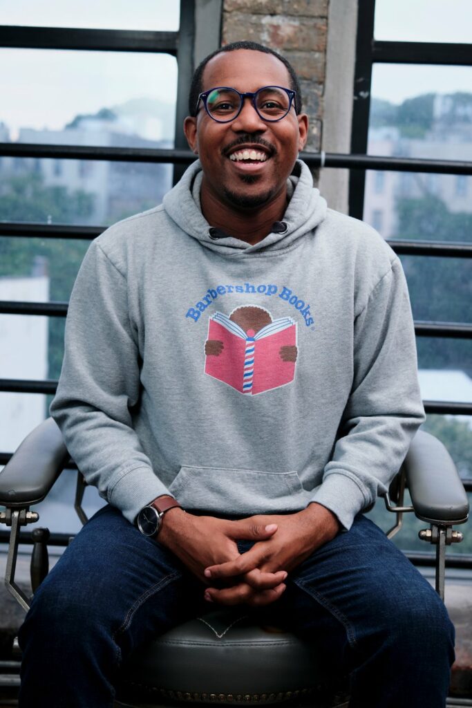 Picture of Barbershop Books Executive Director Alvin Irby smiling, wearing a Barbershop Books sweatshirt.