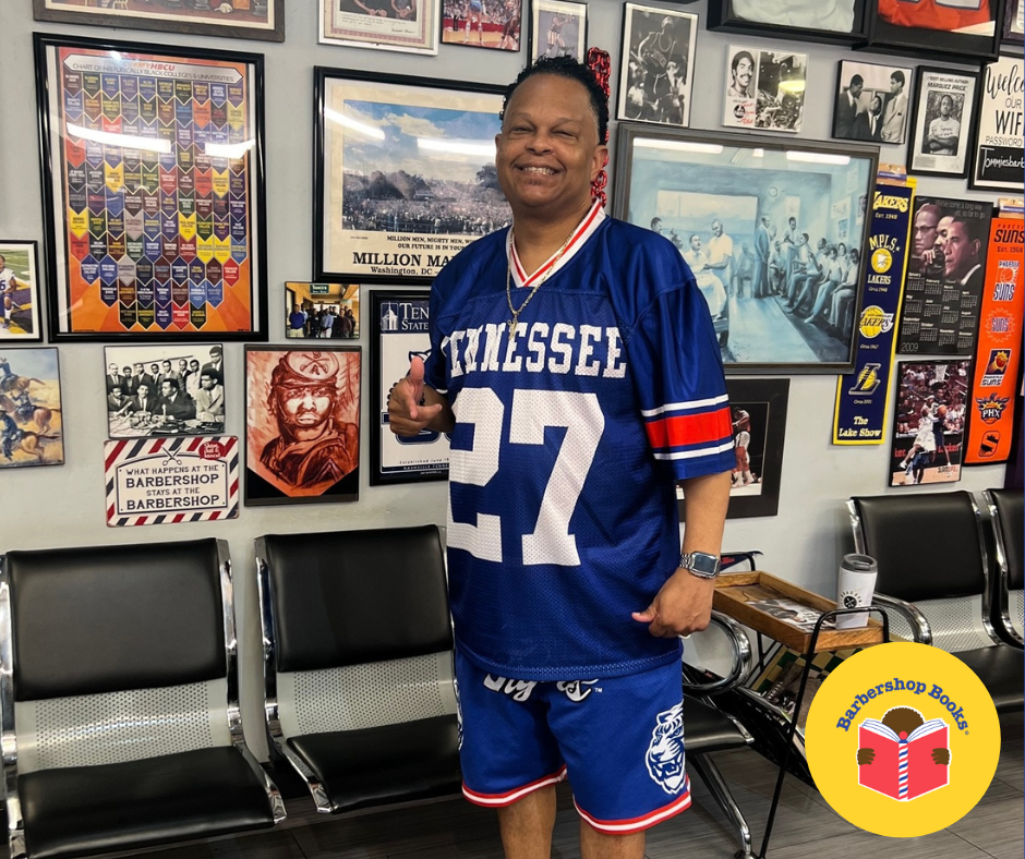 Man in blue jersey with a thumbs up standing in a barbershop